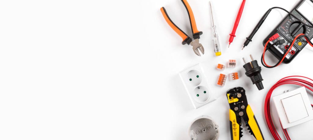 Assorted electrical tools and components, including pliers, screwdrivers, and a multimeter, crucial for an electrician's fault finding or consumer unit upgrade tasks, like wire strippers, power sockets, connectors, plugs, switches, and wiring are neatly arranged against a white background.